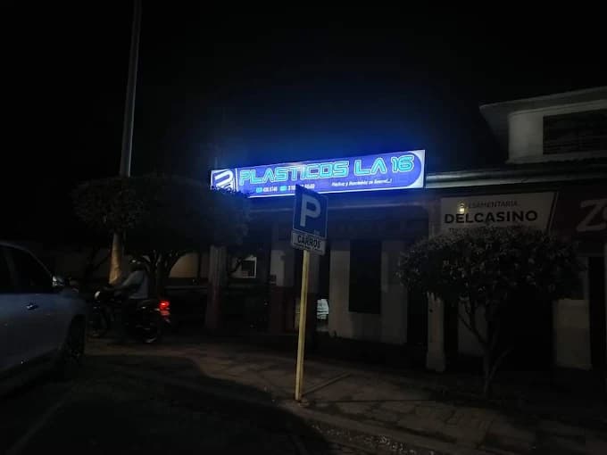 Fachada iluminada de Plásticos La 16 en la calle 16, de noche